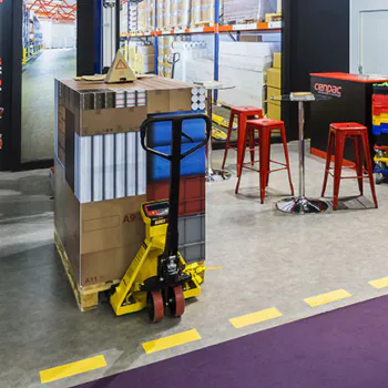 Transpalette peseur Transérénité soulevant une palette de cartons en entrepôt pour le contrôle à réception